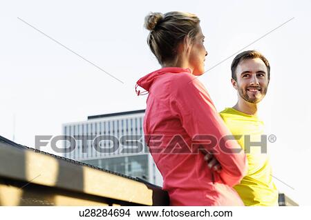 Picture - Young male and female runners talking on bridge. Fotosearch