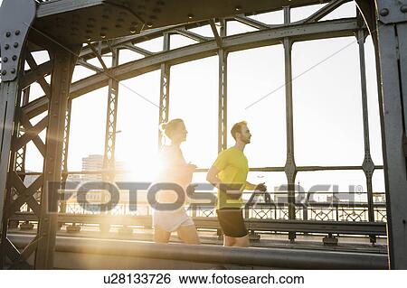 Young male and female running across bridge View Large Photo Image Stock Photograph - Young male and female running across bridge. Fotosearch