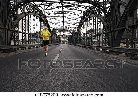 Stock Photo - Young male athlete running on bridge. Fotosearch
