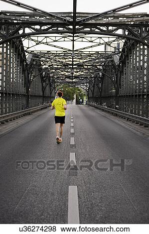 Stock Photo - Young male athlete running over bridge. Fotosearch