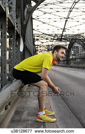 Young male runner resting on bridge View Large Photo Image Stock Photo - Young male runner resting on bridge. Fotosearch
