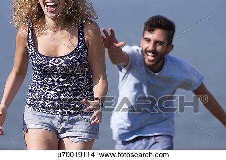 Picture - Young man chasing woman, laughing. Fotosearch