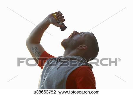 Stock Image - Young man drinking sports gel. Fotosearch