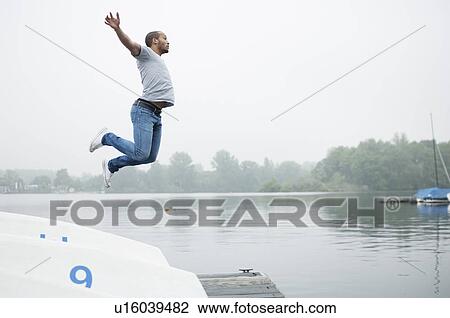 Young man jumping into lake View Large Photo Image Stock Image - Young man jumping into lake. Fotosearch