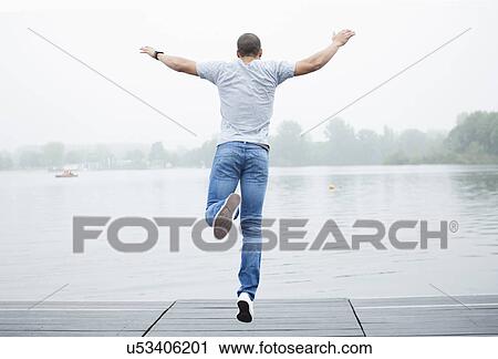 Stock Image - Young man jumping into lake. Fotosearch