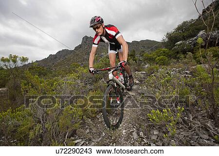 Young man mountain biking down mountain path View Large Photo Image Stock Image - Young man mountain biking down mountain path. Fotosearch