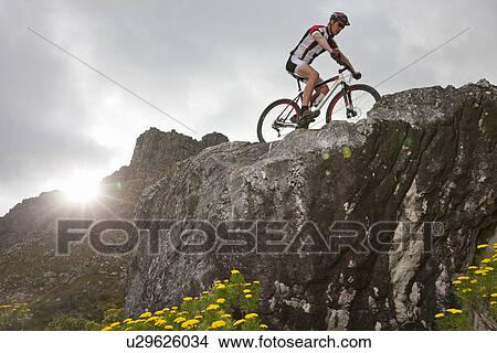 Young man mountain biking on top of rock formation View Large Photo Image Picture - Young man mountain biking on top of rock formation. Fotosearch