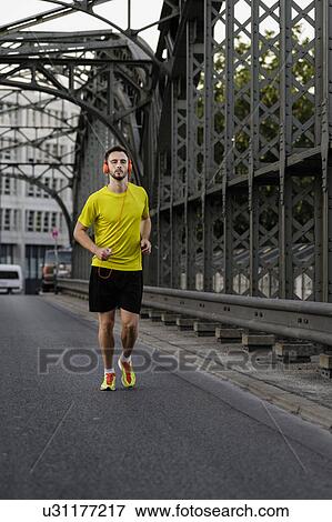 Young man running on bridge View Large Photo Image Stock Photo - Young man running on bridge. Fotosearch
