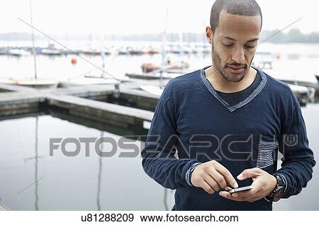 Young man using cell phone View Large Photo Image Stock Photo - Young man using cell phone. Fotosearch