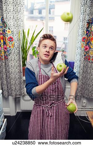 Young man using mobile whilst juggling apples View Large Photo Image Stock Image - Young man using mobile whilst juggling apples. Fotosearch