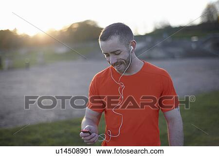 Young man using mp3 player View Large Photo Image Stock Image - Young man using mp3 player. Fotosearch