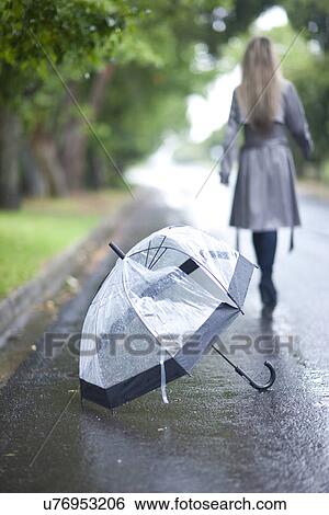 Stock Photograph - Young woman and broken umbrella in park. Fotosearch