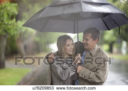 Young woman and mature man walking in rainy park View Large Photo Image Stock Image - Young woman and mature man walking in rainy park. Fotosearch