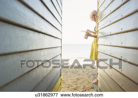 Stock Photo - Young woman having a snack between beach huts. Fotosearch