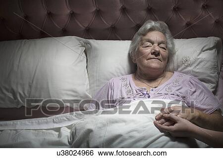 Young woman holding sleeping senior woman's hand View Large Photo Image Stock Photograph - Young woman holding sleeping senior woman's hand. Fotosearch