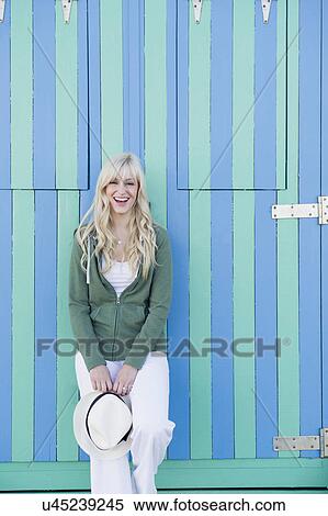 Stock Photography - Young woman in front of striped beach hut. Fotosearch