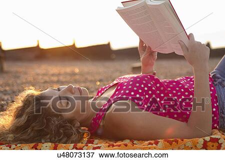 Young woman lying on beach reading book View Large Photo Image Stock Photo - Young woman lying on beach reading book. Fotosearch