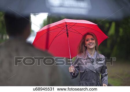 Stock Image - Young woman meeting man in park. Fotosearch