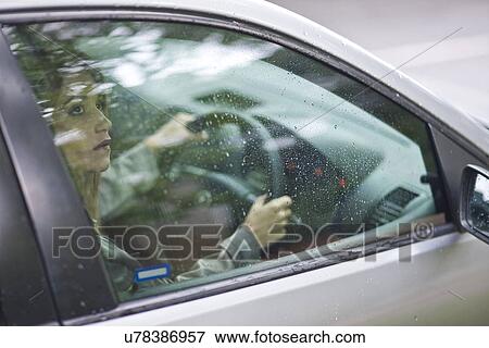Young woman sitting in car looking out of window View Large Photo Image Stock Photo - Young woman sitting in car looking out of window. Fotosearch