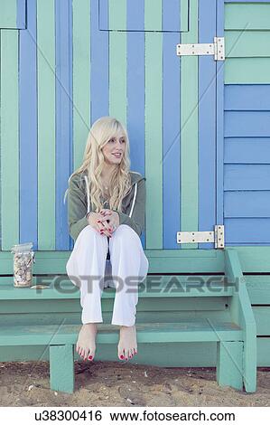 Young woman sitting in front of striped beach hut View Large Photo Image Stock Photograph - Young woman sitting in front of striped beach hut. Fotosearch