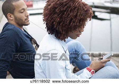 Young woman using cell phone, man watching View Large Photo Image Stock Image - Young woman using cell phone, man watching. Fotosearch