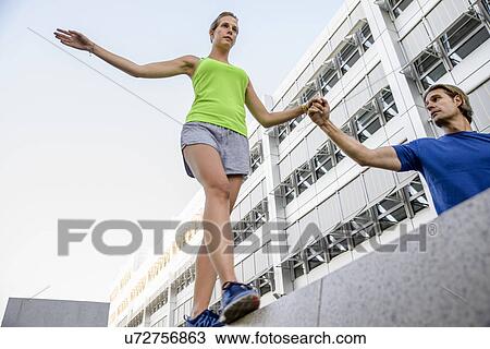 Young woman walking on wall holding man's hand View Large Photo Image Stock Image - Young woman walking on wall holding man's hand. Fotosearch