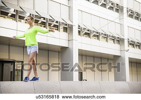 Stock Photo - Young woman walking on wall. Fotosearch
