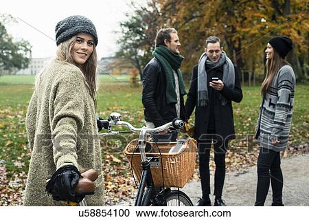 Young woman with bike, friends in background View Large Photo Image Stock Image - Young woman with bike, friends in background. Fotosearch