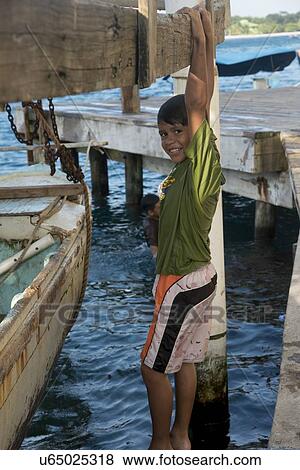 Boy hanging from a dock, Cayman Cay, Utila Island, Bay Islands, Honduras View Large Photo Image Stock Photo - Boy hanging from a dock, Cayman Cay, Utila Island, Bay Islands, Honduras. Fotosearch