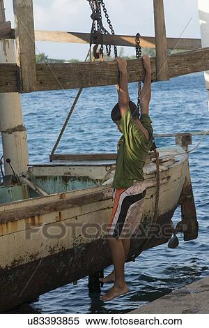 Stock Photography - Boy hanging from a dock, Cayman Cay, Utila Island, Bay Islands, Honduras. Fotosearch