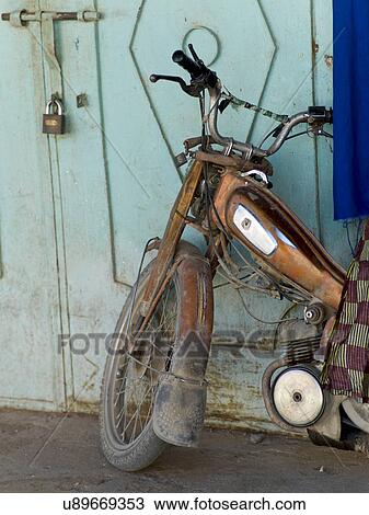 Stock Image - Close-up of a motorcycle in front of doorway, Tamzawrout, Morocco. Fotosearch