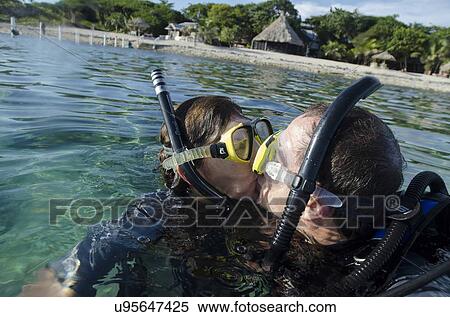 Couple kissing with scuba gears in the sea, Utopia Village, Utila, Bay Islands, Honduras View Large Photo Image Stock Photography - Couple kissing with scuba gears in the sea, Utopia Village, Utila, Bay Islands, Honduras. Fotosearch