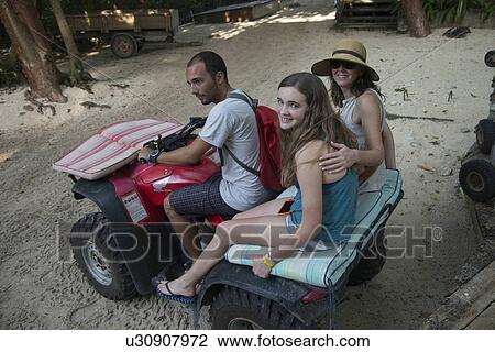 Stock Image - Family enjoying quadbike riding on beach, Utila, Bay Islands, Honduras. Fotosearch