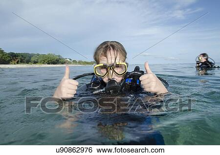 Stock Photograph - Female scuba diver showing thumbs up in the sea, Utila, Bay Islands, Honduras. Fotosearch