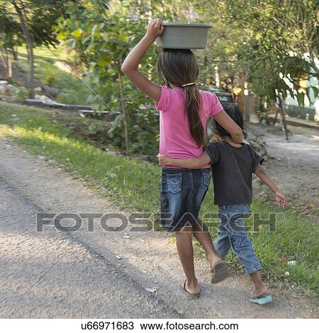 Stock Image - Girl carrying a pot on head at roadside, Copan, Copan Ruinas, Honduras. Fotosearch