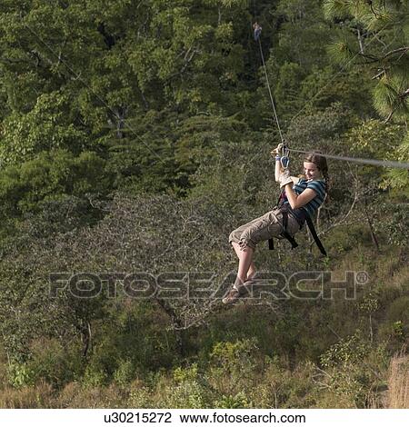 Stock Image - Girl riding a zip line in a forest, Copan, Copan Ruinas, Copan Department, Honduras. Fotosearch