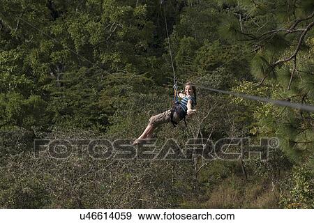 Stock Photo - Girl riding a zip line in a forest, Copan, Copan Ruinas, Copan Department, Honduras. Fotosearch