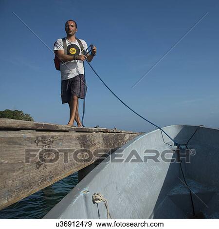 Stock Photo - Man moor the boat at dock, Utila, Bay Islands, Honduras. Fotosearch