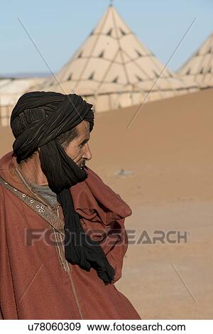 Stock Photo - Man standing in a desert, Erg Chigaga Luxury Desert Camp, Sahara Desert, Morocco. Fotosearch
