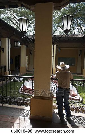 Stock Photo - Man standing on balcony of a hotel, Copan, Copan Ruinas, Honduras. Fotosearch