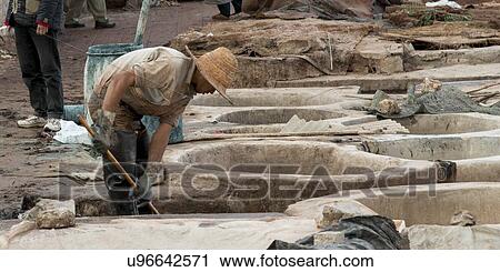 Stock Image - Man working at tannery in medina of Marrakesh, Morocco. Fotosearch