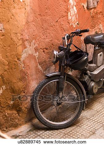 Stock Photography - Moped leaning against a weathered wall, Marrakesh, Morocco. Fotosearch