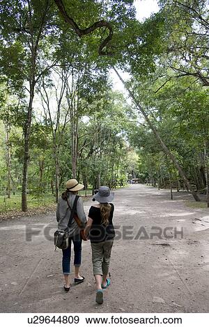 Stock Photo - Rear view of a woman and her daughter walking on the road, Copan, Copan Ruinas, Copan Department, Honduras. Fotosearch