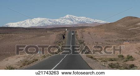 Stock Image - Road leading towards snowcapped mountains, Atlas Mountains, Morocco. Fotosearch