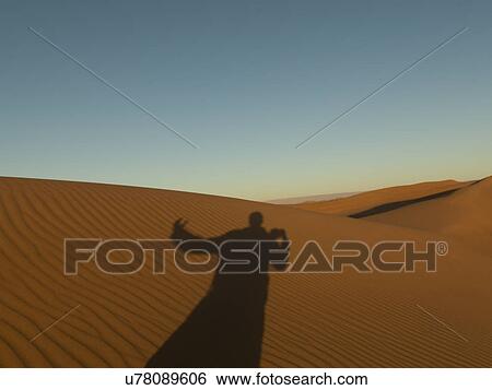 Stock Photograph - Shadow of a person on Erg Chegaga Dunes in Sahara Desert, Souss-Massa-Draa, Morocco. Fotosearch