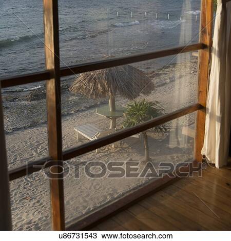 Sunshades with chairs on the beach viewed from window, Utopia Village, Utila, Bay Islands, Honduras View Large Photo Image Stock Image - Sunshades with chairs on the beach viewed from window, Utopia Village, Utila, Bay Islands, Honduras. Fotosearch