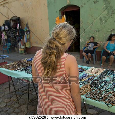 Stock Photography - Teenage girl looking at bead necklace at market stall, Barrio El Centro, Copan, Copan Ruinas, Honduras. Fotosearch