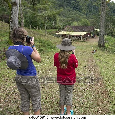 Stock Photography - Two girls taking picture with digital cameras in a farm, Finca El Cisne, Honduras. Fotosearch