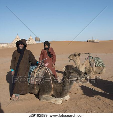 Two Tuareg men standing in a desert with their camels, Erg Chigaga Luxury Desert Camp, Sahara Desert, Morocco View Large Photo Image Stock Photo - Two Tuareg men standing in a desert with their camels, Erg Chigaga Luxury Desert Camp, Sahara Desert, Morocco. Fotosearch