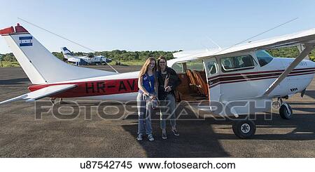 Stock Photography - Two women standing in front of a seaplane and smiling, Bay Islands, Honduras. Fotosearch